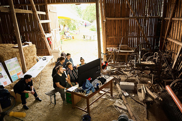 Jugendliche sitzen in einer Scheune vor einem Monitor