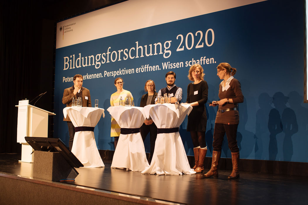 Sechs Personen stehen auf der Bühne, vor einem Plakat mit dem Titel Bildungsforschungstagung 2020